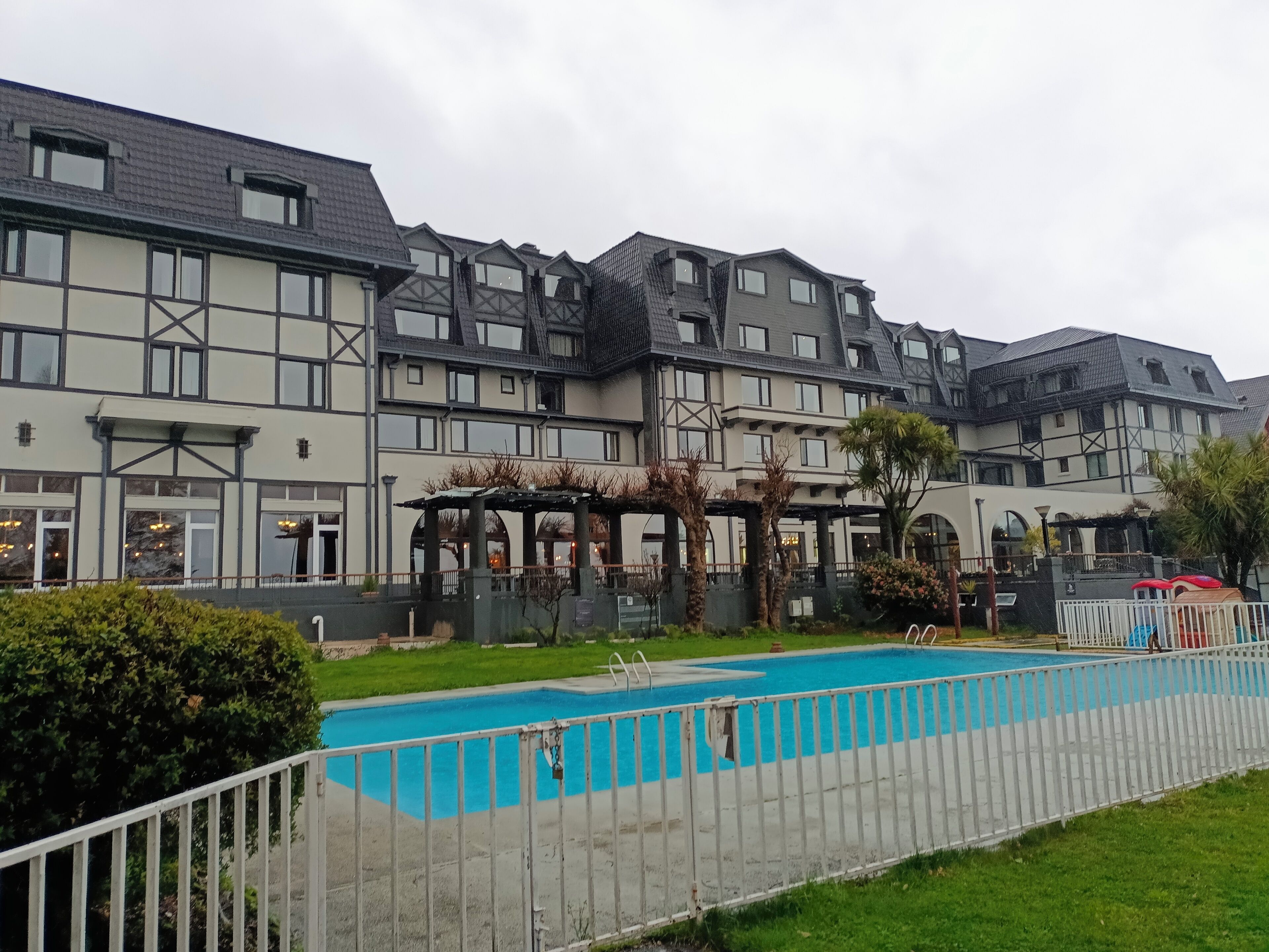 Un hotel con piscina, varios balcones y un espacio al aire libre cubierto.