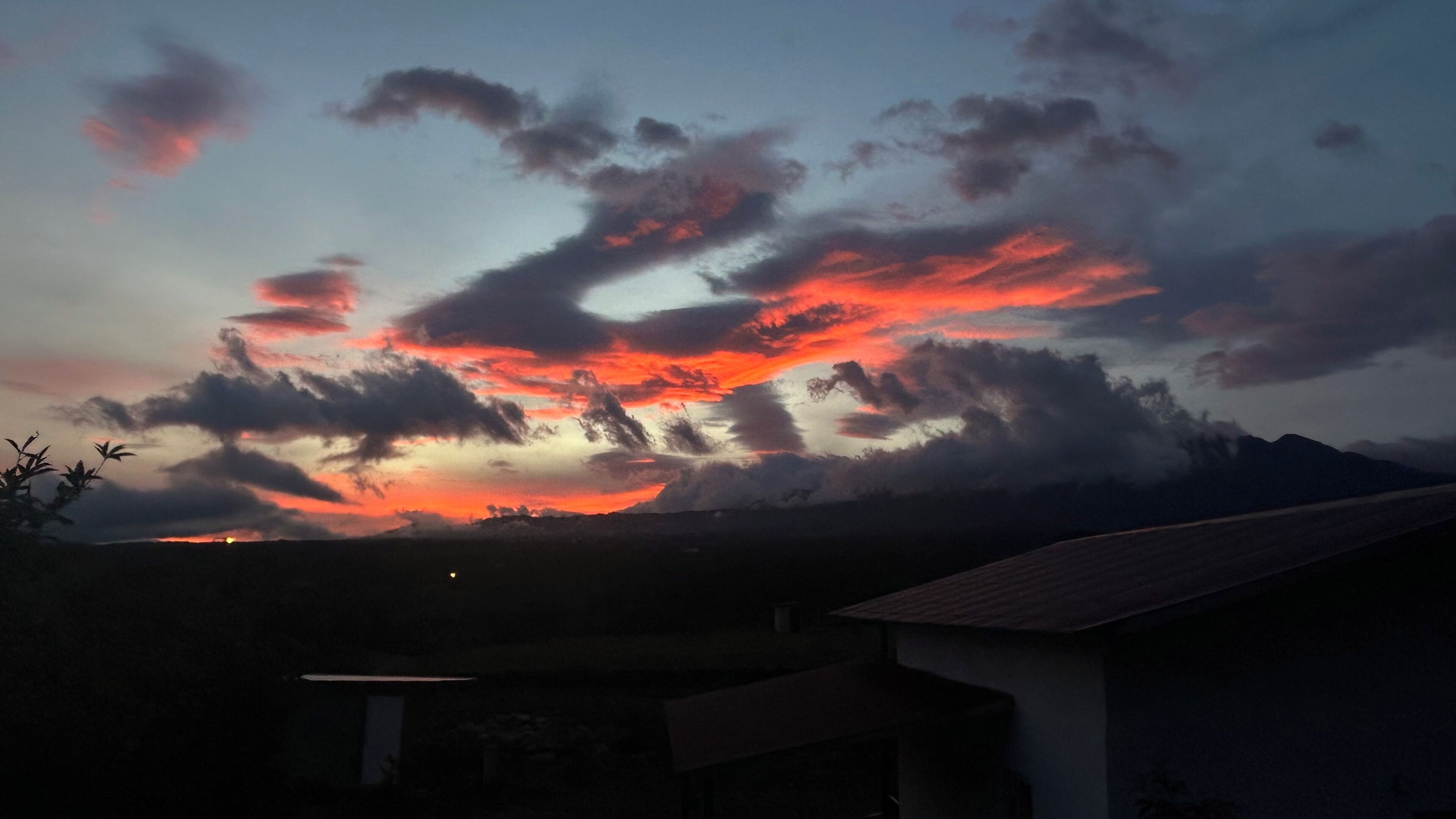Un atardecer con nubes sobre un paisaje montañoso.