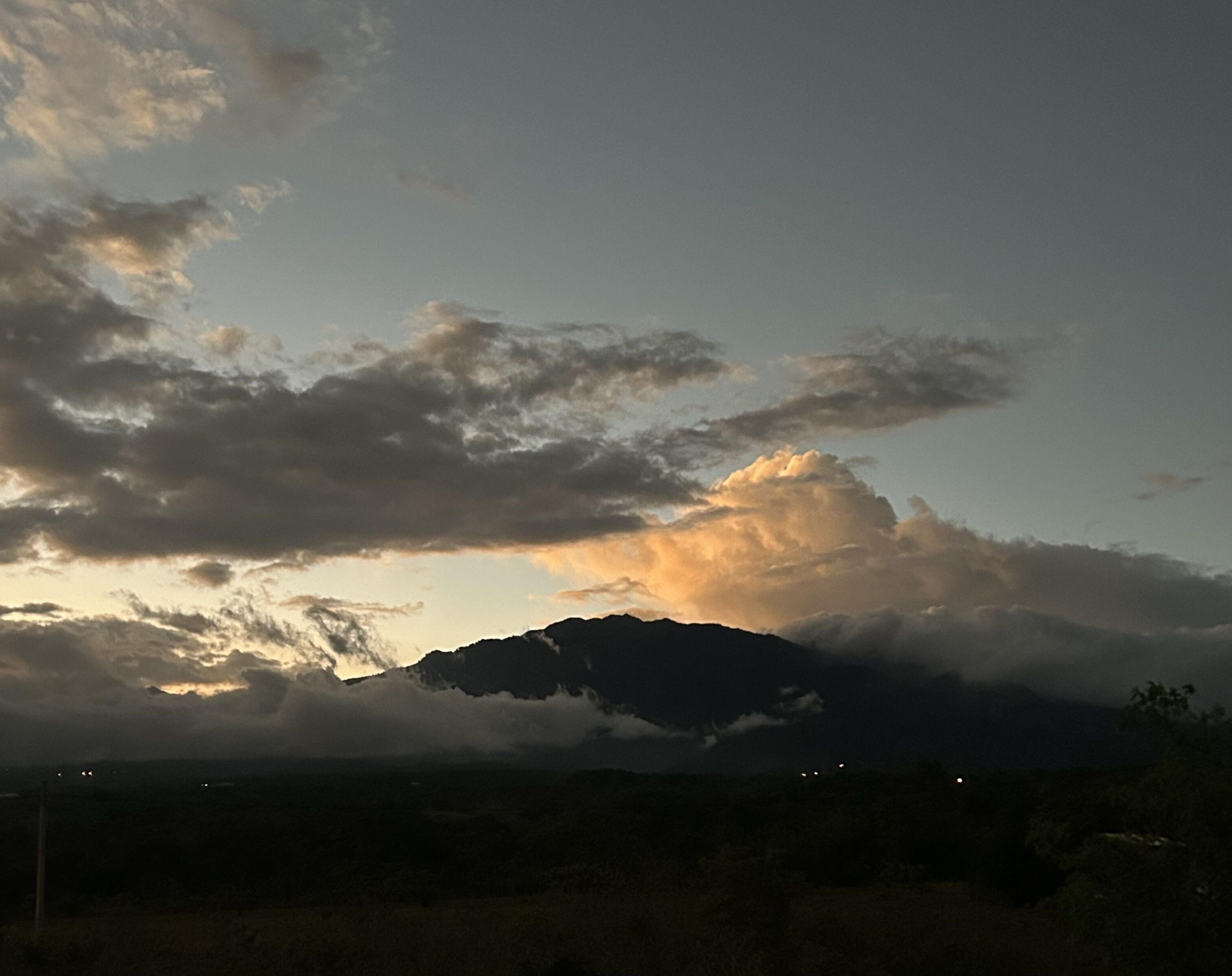 Paesaggio montano con nuvole e un tramonto.
