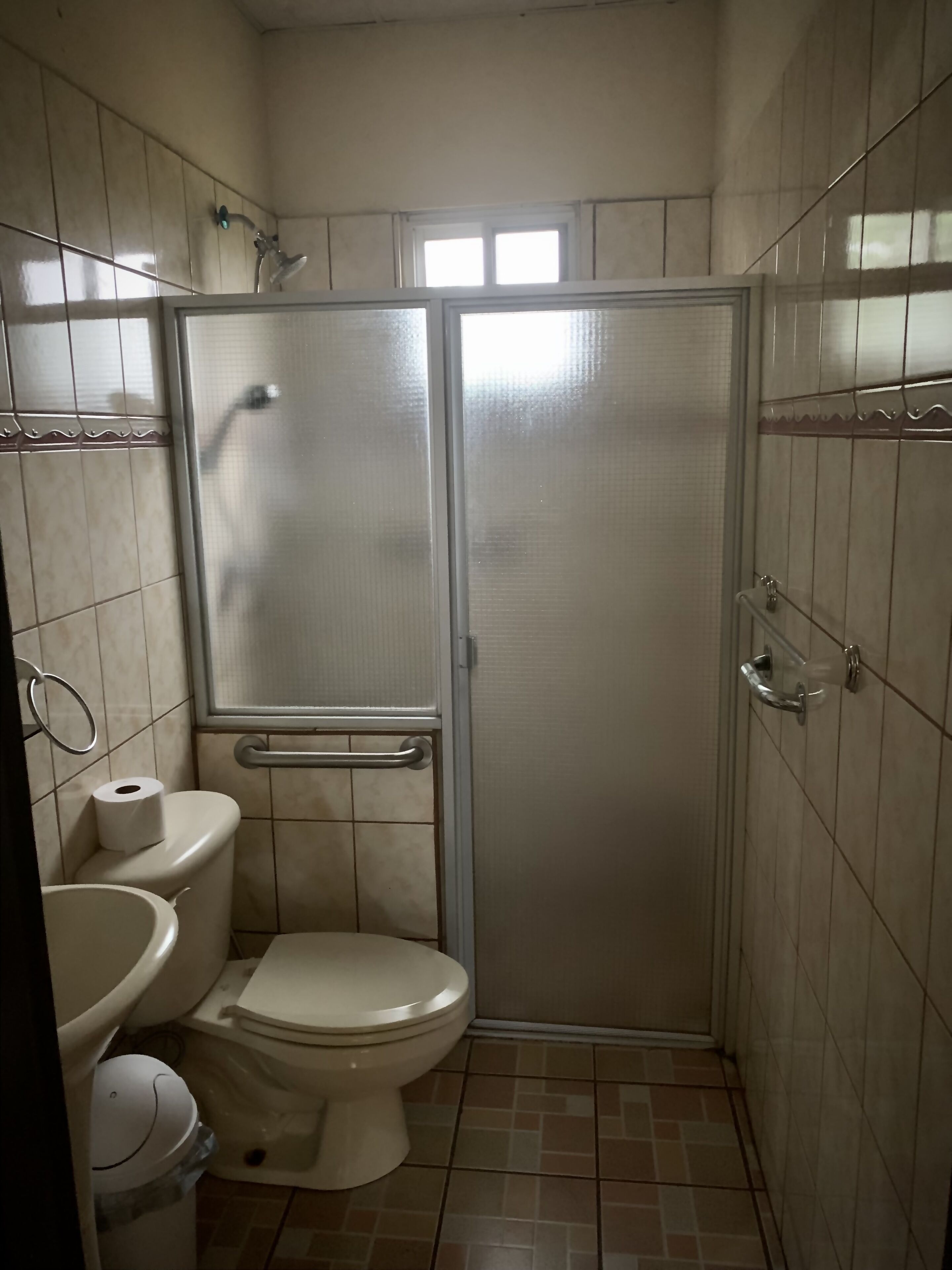 A small, tiled bathroom with a toilet, bidet, and shower stall.