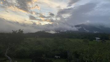 Eine Landschaft mit einem Berg im Hintergrund und einem bewölkten Himmel.
