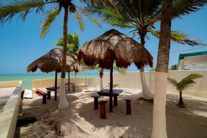 A beachside area with thatched umbrellas, wooden tables, and benches. - Flamingos Inn (Progreso)