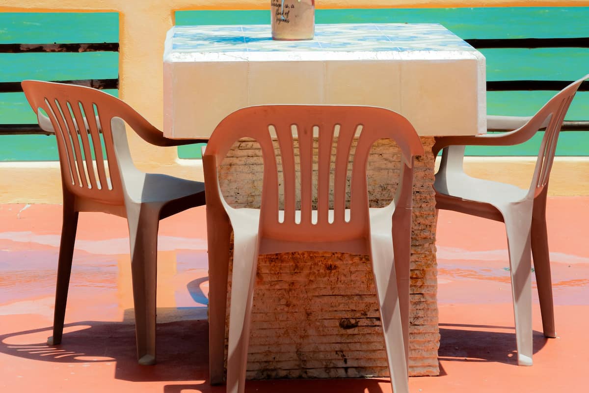 A table with a bottle and a decorative item, two chairs, and a view of the ocean.