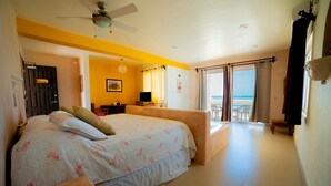 Ein Schlafzimmer mit Bett, Schreibtisch, Stuhl und Blick auf den Strand.