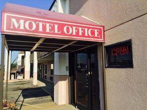 A motel office with a red awning and an 'OPEN' sign. - Deluxe Inn (West Memphis)