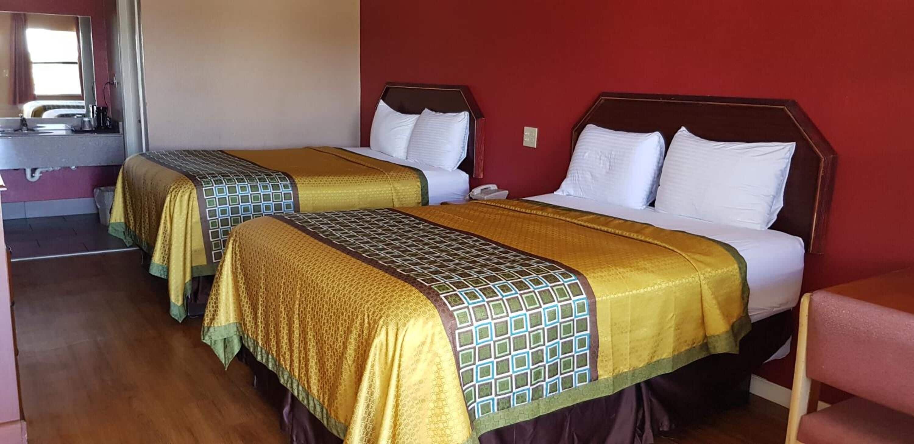 Hotellihuoneessa on kaksi sänkyä, joissa on molemmissa kuviollinen päiväpeite ja tyynyjä. Sängyn päädyssä on puinen koristepaneeli, huoneessa on yöpöytä ja seinällä peili.