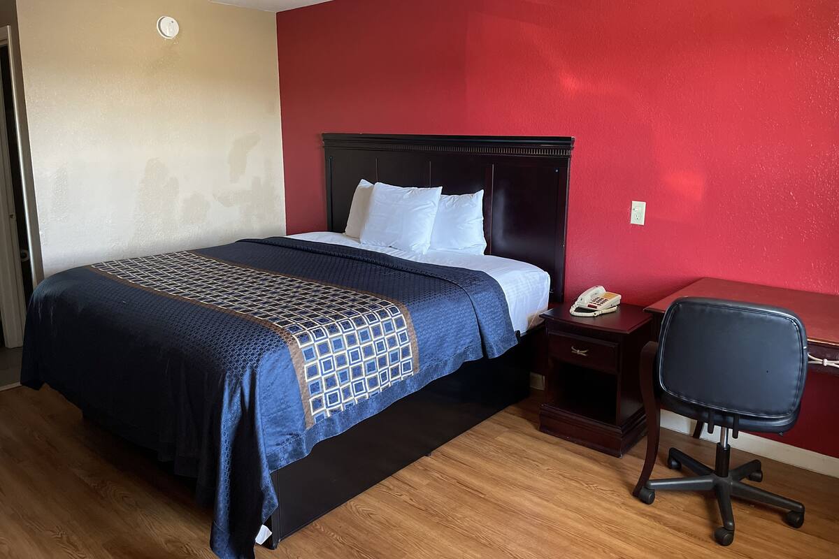A hotel room with a bed, a desk, a chair, and a telephone.