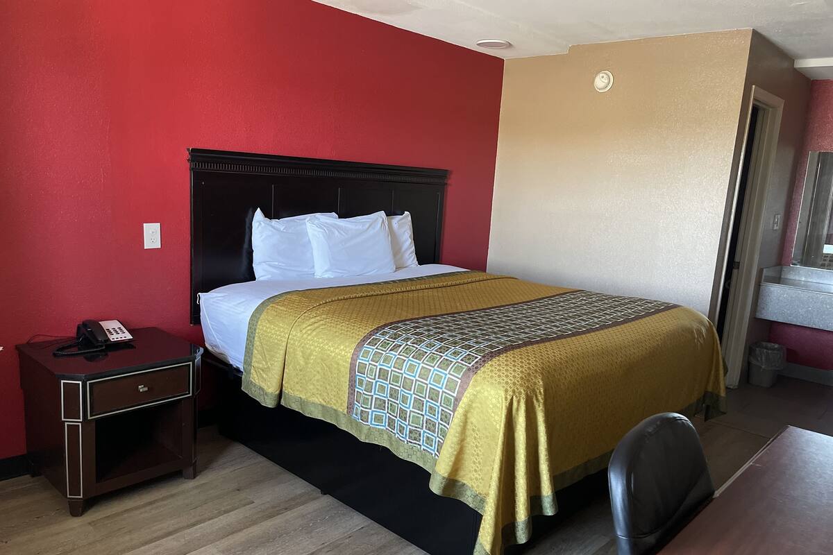 A hotel room with a bed, a nightstand, a desk, and a chair.