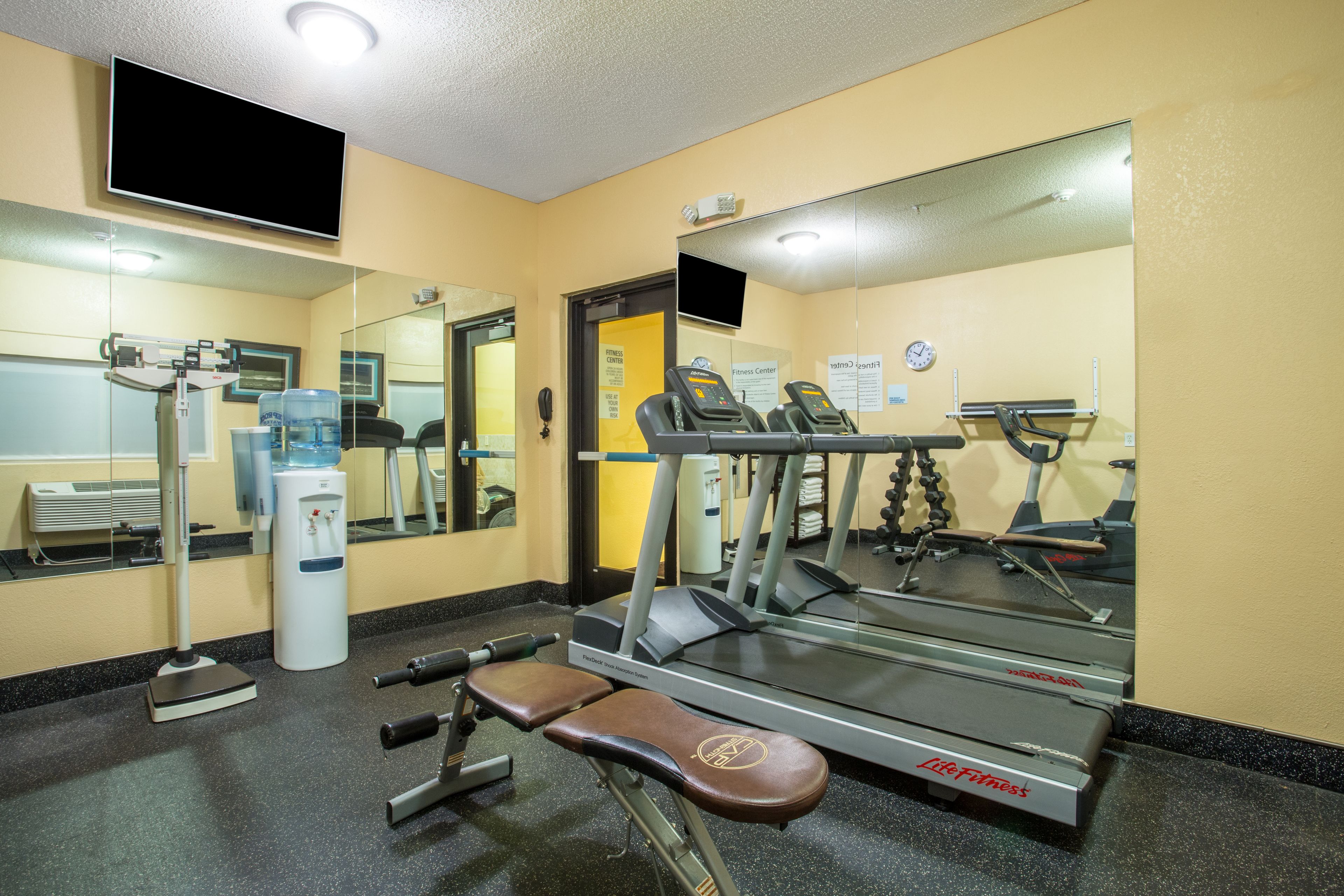 Une salle de sport équipée de matériel d’exercice, d’un distributeur d’eau et d’un tapis de course.