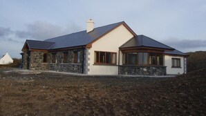 A two-story house with a stone facade, a pitched roof, and a chimney.