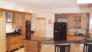 A spacious kitchen with wooden cabinets, a large island with bar stools, and modern appliances.