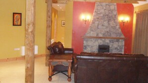 A living room with a stone fireplace, leather sofa, and wooden coffee table.