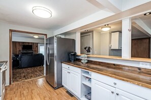 A modern kitchen with wooden flooring, white cabinets, a stainless steel refrigerator, and a wooden countertop. - Nashville Lakehouse on Old Hickory, Two Foot Cove! (Mt Juliet)