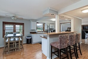 A modern kitchen with a central island, bar stools, and a dining table with chairs. - Nashville Lakehouse on Old Hickory, Two Foot Cove! (Mt Juliet)