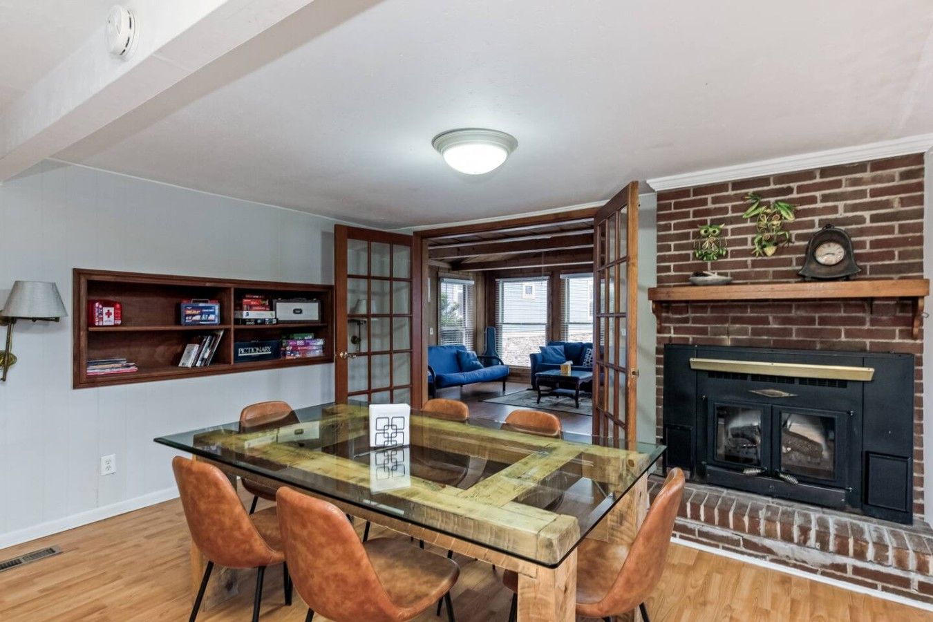 Un coin repas avec une table et des chaises en verre, une cheminée et une bibliothèque remplie de livres.