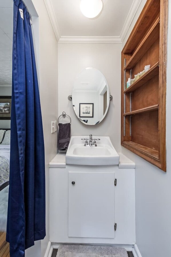 A bathroom with a white sink, a mirror, and a wooden medicine cabinet.