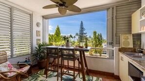 Een balkon met een tafel, stoelen en een bloempot.