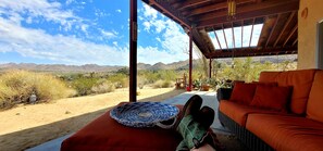 A covered outdoor seating area with a view of desert landscape and mountains.