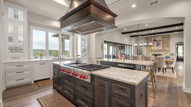 A spacious kitchen with a large island, dark cabinetry, and a modern stove. - High-end Home on 33 Acres to Roam, Short Drive to Downtown. (Austin)