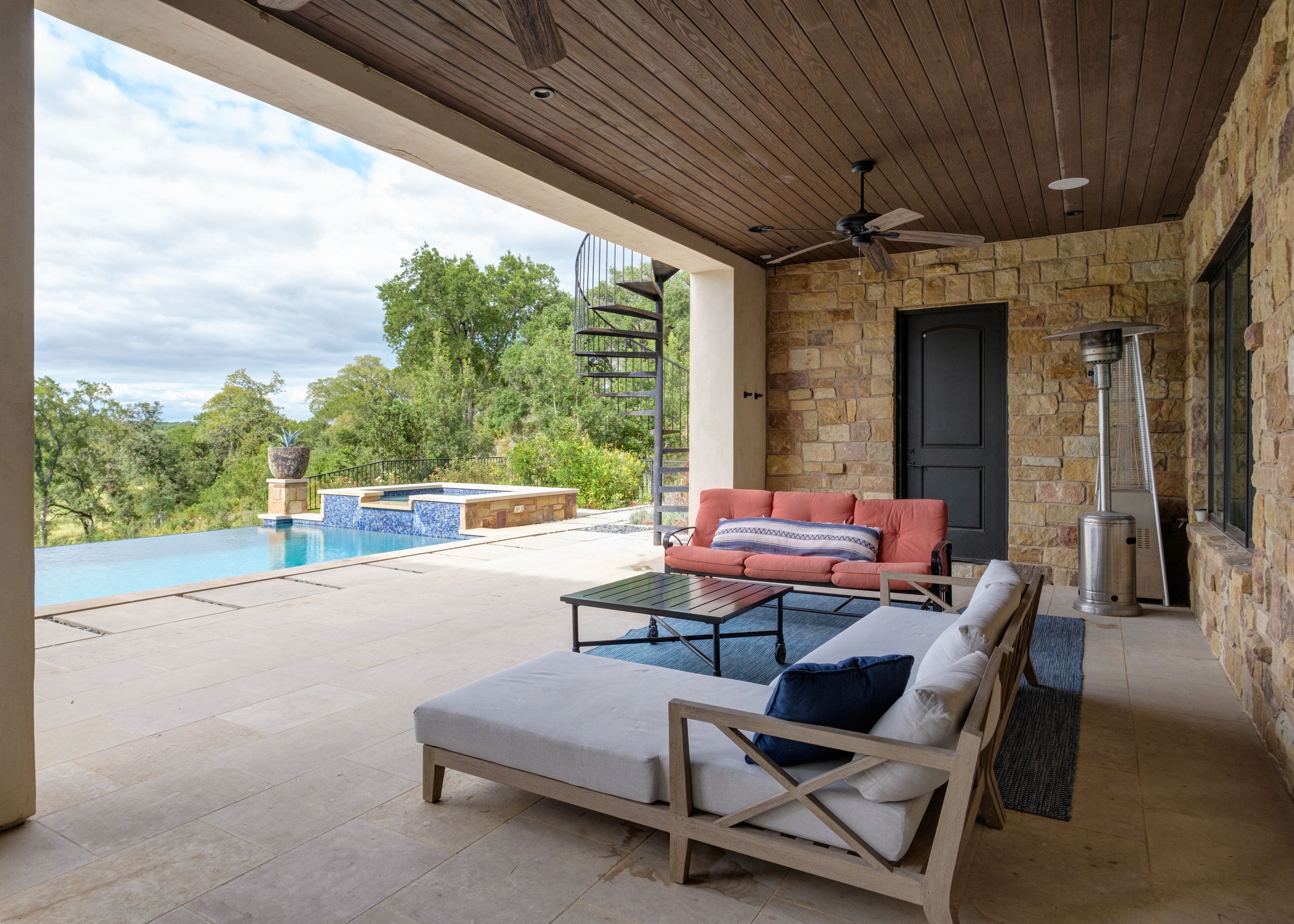 Un espacio al aire libre cubierto con piscina, asientos y un muro de piedra.