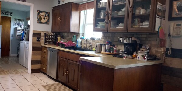 A kitchen with wooden cabinets, a dishwasher, a coffee maker, and various kitchen items on the counter.