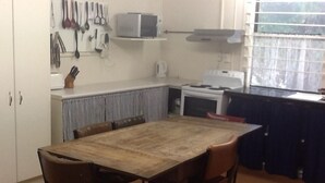 Una cucina compatta con un tavolo e sedie in legno, un forno a microonde e un fornello.