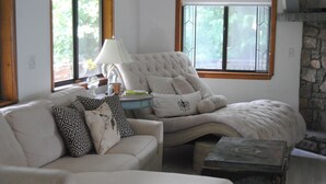 Ein Wohnzimmer mit einer Couch, einem Sessel, einer Lampe und einem Kamin aus Stein.