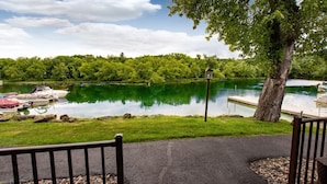 A lakeside view with boats docked, a dock, and a tree in the foreground.
