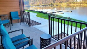 A balcony with outdoor seating, a view of a lake, and a dock.