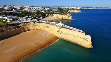 Une zone côtière comprenant une plage de sable, une falaise et un bâtiment blanc doté d’un toit en forme de flèche.