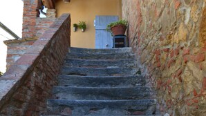 Un escalier en pierre menant à un bâtiment doté d’un plafond en bois et de jardinières suspendues.