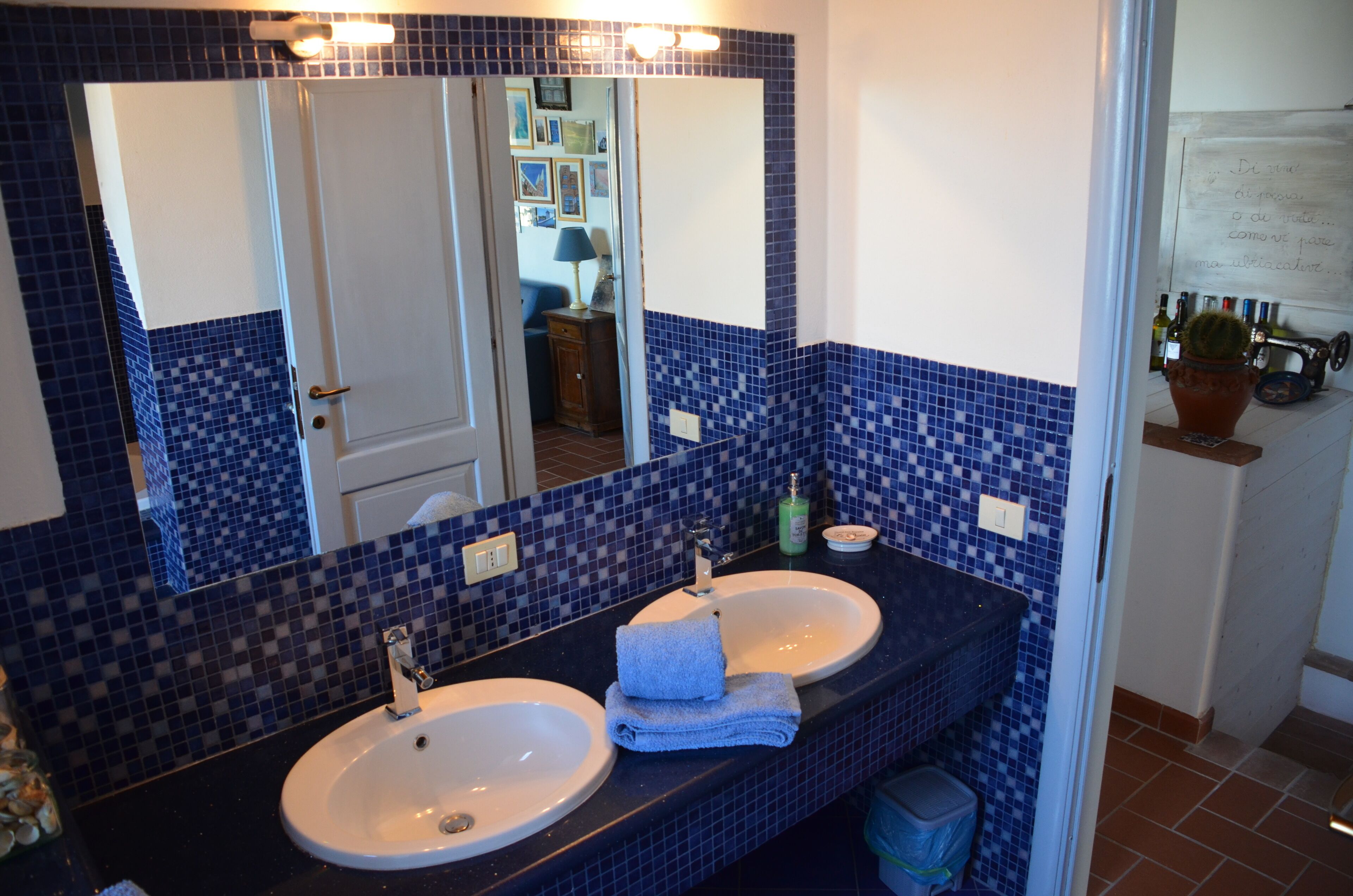 Un baño con dos lavamanos, un espejo grande y paredes de azulejos azules.