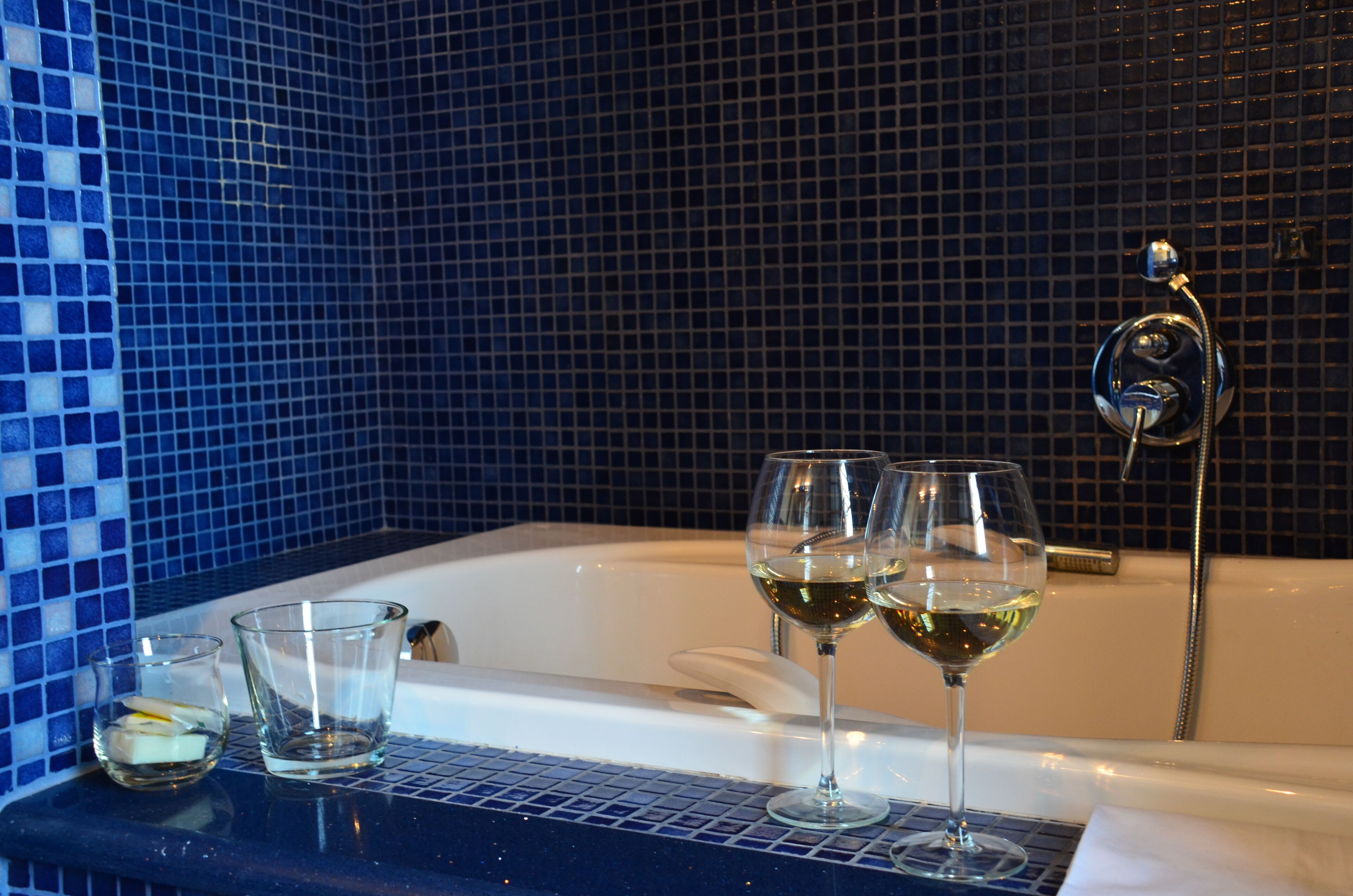 Eine Badewanne mit zwei Gläsern Weißwein und einem kleinen Glas mit Zitronenscheibe.
