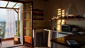 Une cuisine compacte dotée d’un plan de travail en bois, d’un four à micro-ondes, d’un grille-pain et d’un luminaire suspendu.