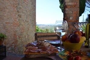 A table with a glass of white wine, a bowl of fruit, and a plate of cured meats. - Casa Magnolia Enjoy unrivaled view and breathtaking sunsets - CIELO (Terricciola)