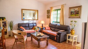 A living room with two sofas, a coffee table, a chair, a lamp, and a vase with flowers.