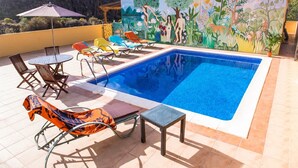 A swimming pool with lounge chairs and a mural on the wall.