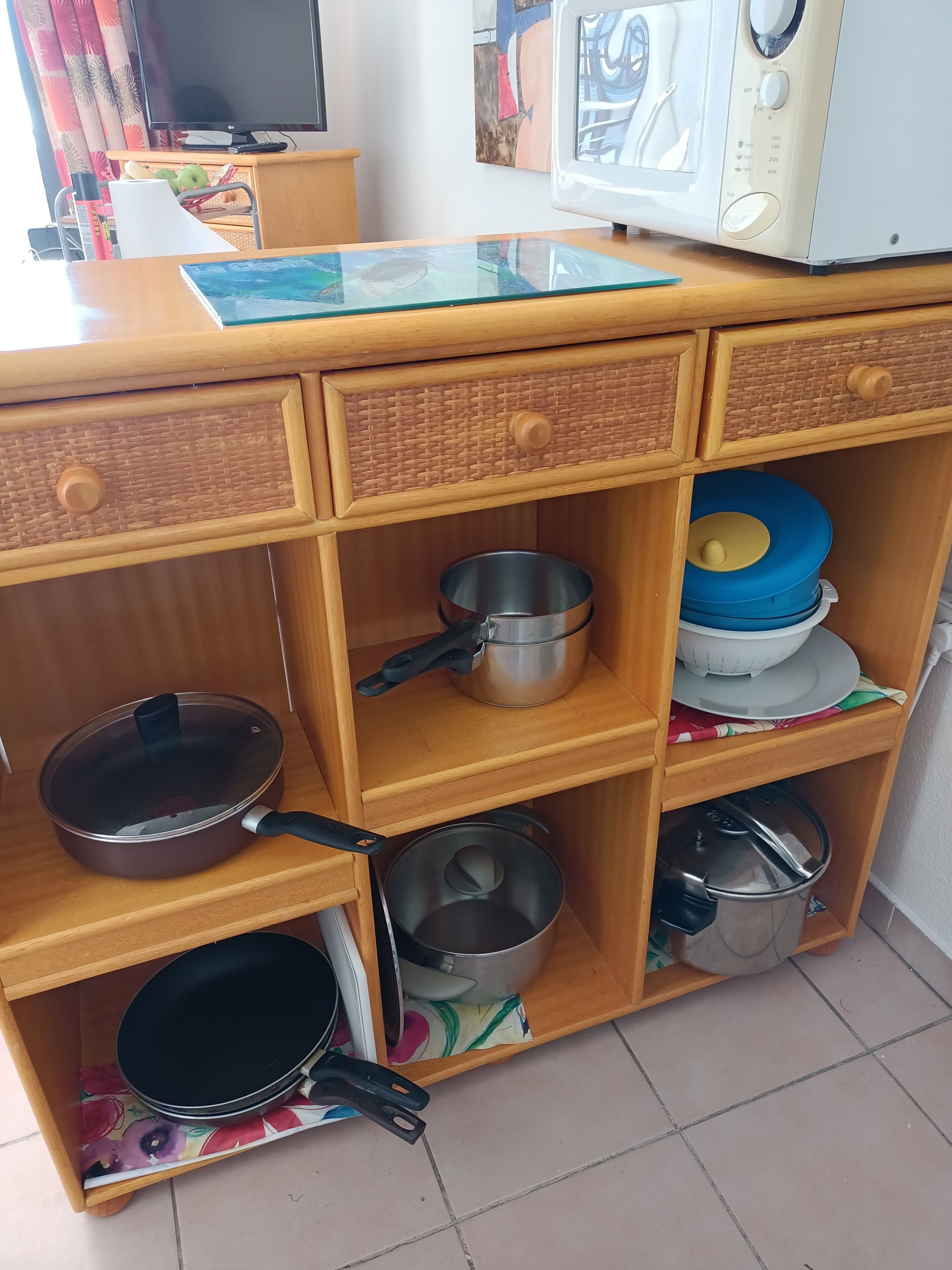 A kitchen with wooden cabinets, a microwave, and various pots and pans.