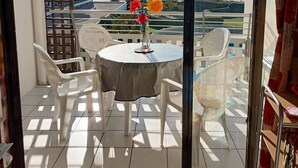 A balcony with a table and chairs, a view of the sea, and a building in the background. - 1st line, sea view, pool and Fort Brescou   (CAP D'AGDE)