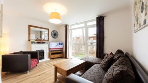 Una sala de estar moderna con un sofá, una mesa de centro, un televisor y una chimenea.