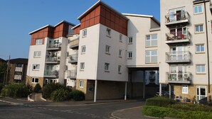 Un edificio residencial de varios pisos con balcones, entrada de garaje y cielo despejado.