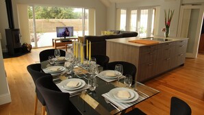 A dining area with a table set for four, a kitchen with a large island, and a TV in the background. - Open Plan Holiday Cottage Within Walking Distance Of Westbourne And Beach (Poole)