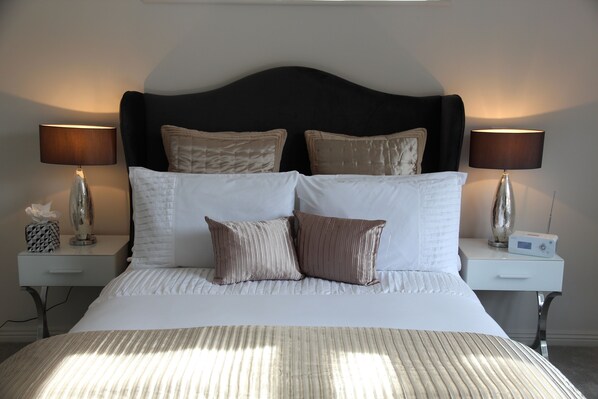 A neatly made bed with white and brown bedding, two bedside tables with lamps, and a modern headboard.