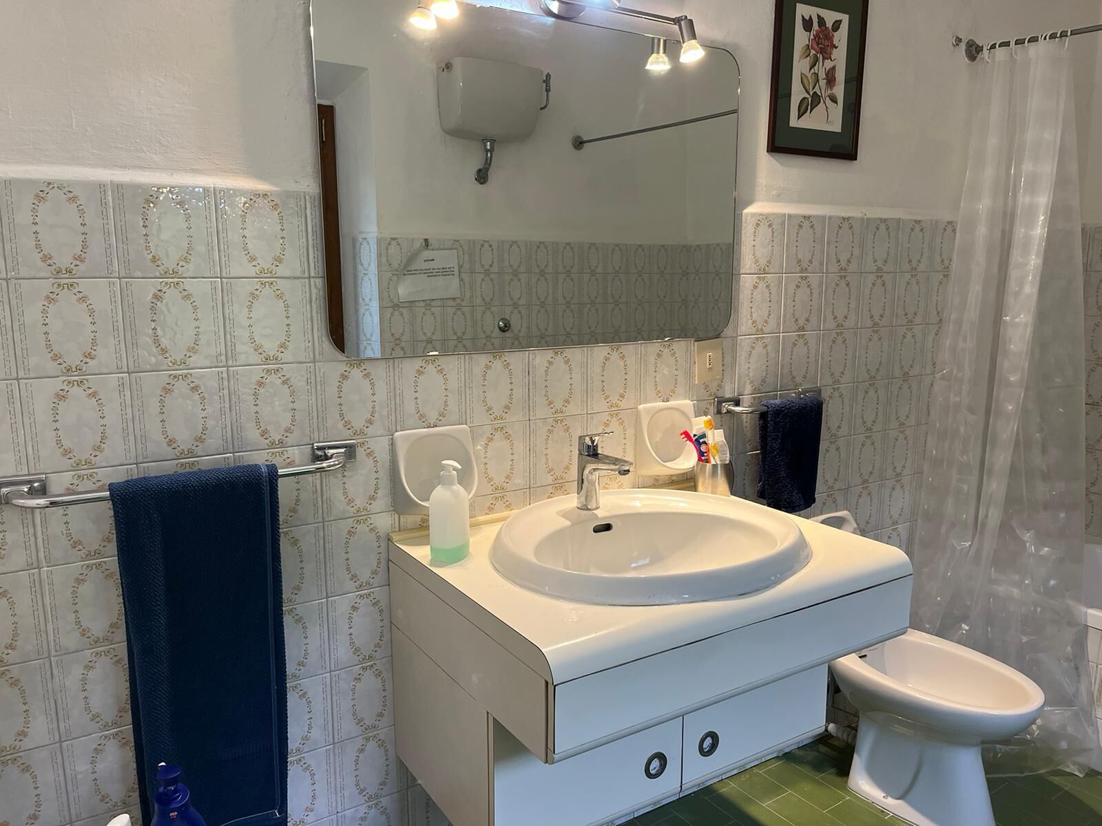 A bathroom with a white sink, a mirror, a toilet, and a shower curtain.