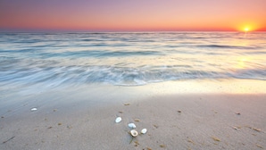A beach with calm waves and a sunset. - PG Beach House II - seaside serenity blends with refined comfort (Sintra)