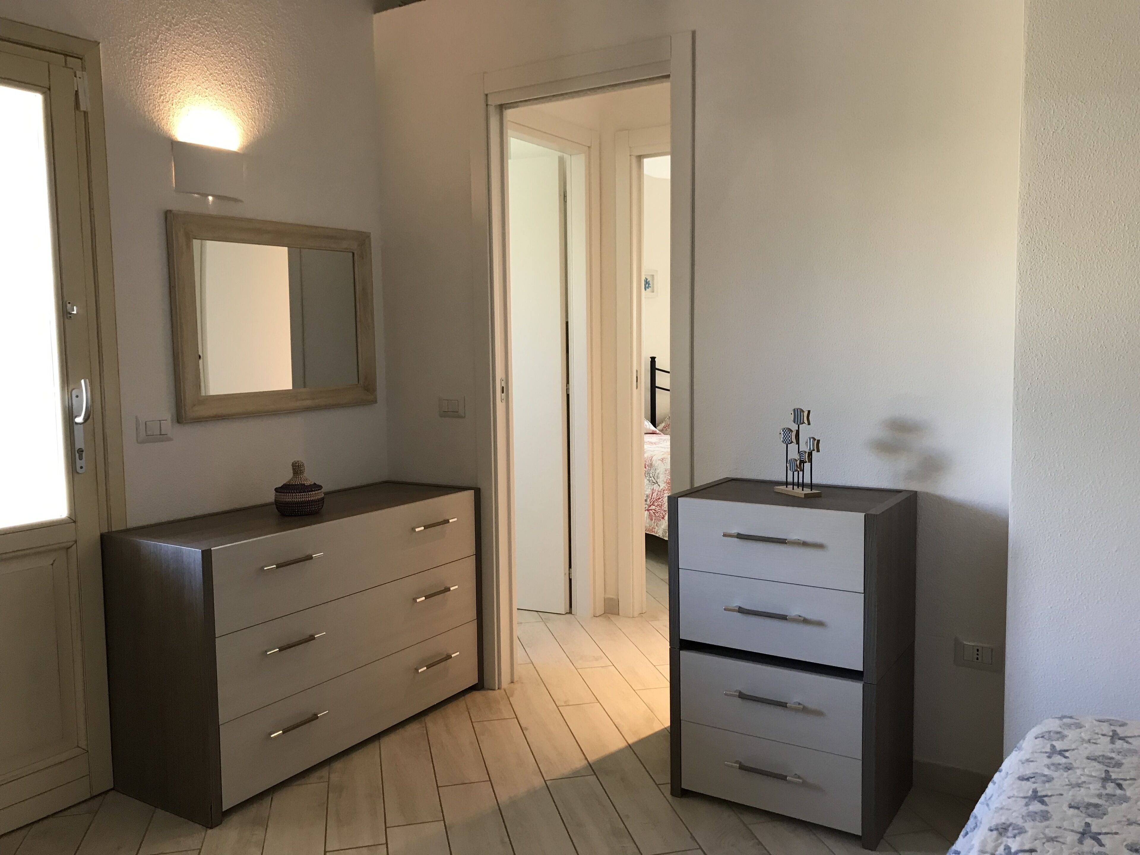 A bedroom with a dresser, a bedside table, and a bed.