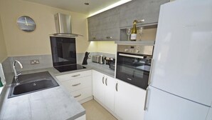 A modern kitchen with a stainless steel sink, a built-in oven, a microwave, and a refrigerator. - Boutique style centrally located terrace, award winning Skipton Yorkshire Dales (Skipton)