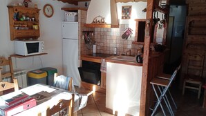 Une cuisine rustique équipée d’un réfrigérateur, d’un four à micro-ondes et de meubles de rangement en bois.