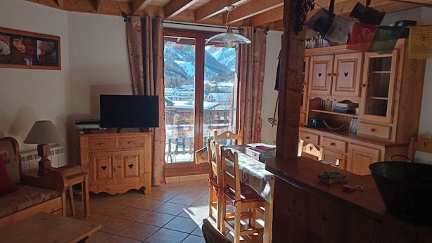 Un intérieur chaleureux en bois, avec une télévision, des meubles en bois et un coin repas comprenant des chaises et une table.