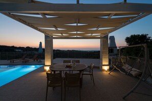 Een buitenzwembad, ligstoelen bij het zwembad